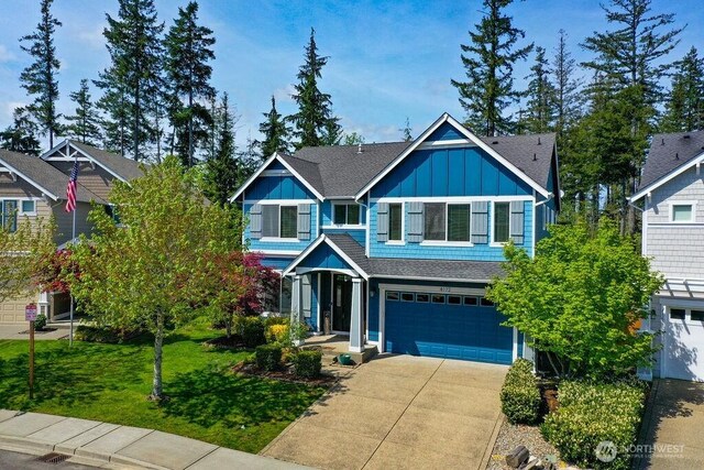 craftsman-style house with a garage, a front lawn, roof with shingles, board and batten siding, and concrete driveway
