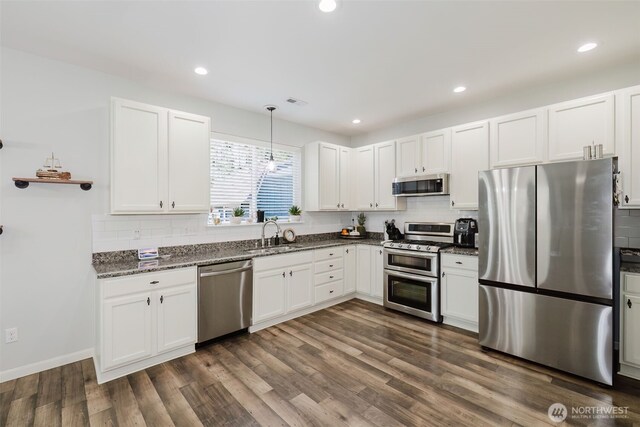 kitchen featuring decorative backsplash, a sink, appliances with stainless steel finishes, and white cabinetry