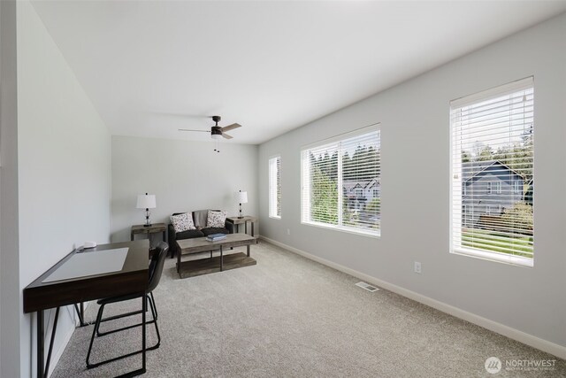 interior space featuring baseboards, ceiling fan, light colored carpet, and visible vents