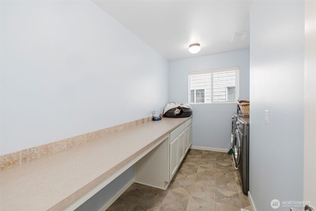washroom featuring washing machine and clothes dryer, baseboards, and cabinet space