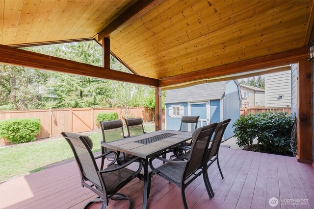 deck with a shed, a fenced backyard, an outbuilding, outdoor dining area, and a yard