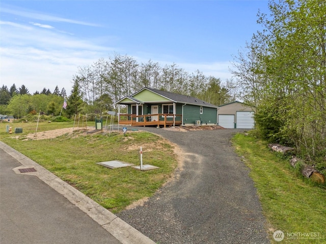 bungalow-style house with covered porch, an outbuilding, a front yard, and a garage