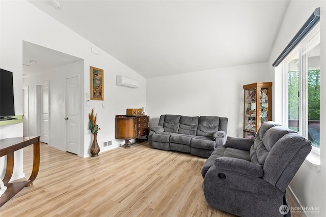 living area with light wood-style floors, high vaulted ceiling, a wall unit AC, and visible vents