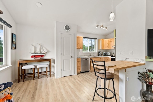 kitchen featuring a kitchen breakfast bar, light brown cabinetry, dishwasher, a sink, and light wood finished floors