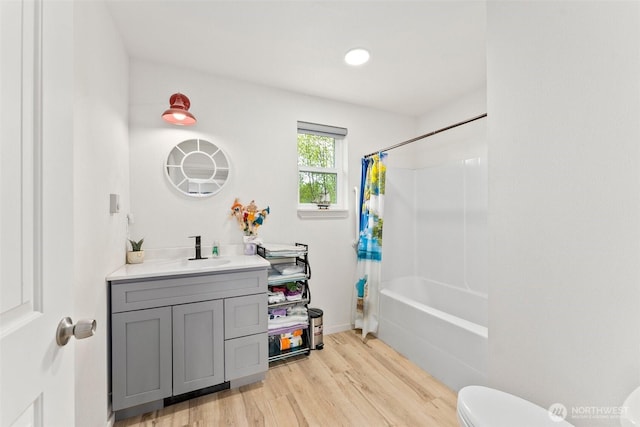 full bathroom featuring vanity, wood finished floors, toilet, baseboards, and shower / bath combo