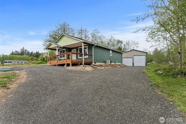 view of front of property featuring a detached garage, an outdoor structure, a porch, and driveway