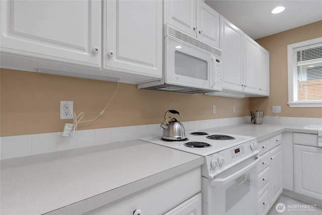 kitchen featuring recessed lighting, light countertops, white cabinets, and white appliances