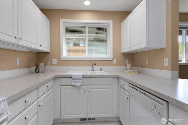 kitchen with white cabinets, a sink, dishwasher, light countertops, and visible vents