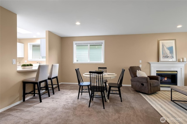 dining space with a fireplace, baseboards, carpet, and a wealth of natural light