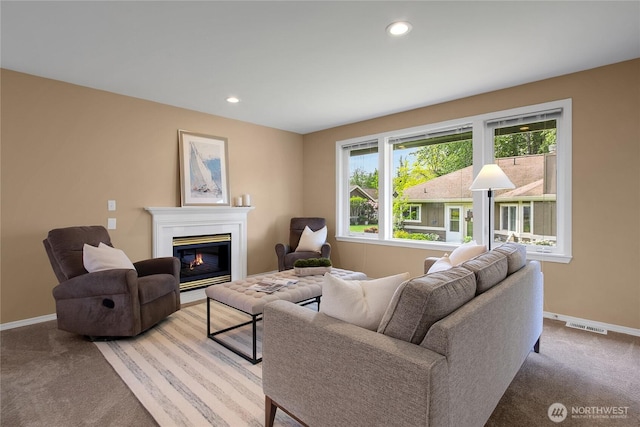 living room with visible vents, a glass covered fireplace, baseboards, recessed lighting, and carpet