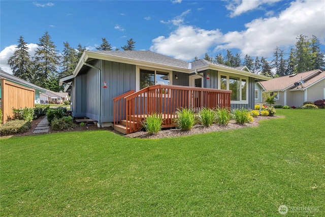 back of house with a lawn, a wooden deck, and board and batten siding