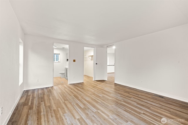 unfurnished living room featuring visible vents, light wood finished floors, and baseboards