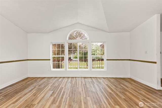 unfurnished room with baseboards, wood finished floors, and lofted ceiling