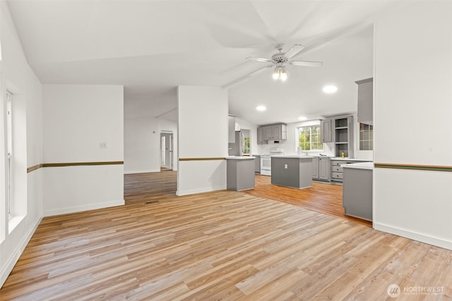 interior space with white electric stove, light countertops, gray cabinets, light wood-style flooring, and vaulted ceiling
