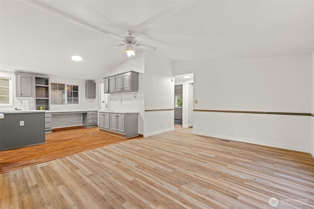 kitchen with ceiling fan, light countertops, gray cabinets, light wood-style flooring, and vaulted ceiling