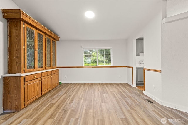 interior space featuring visible vents, light wood finished floors, and baseboards