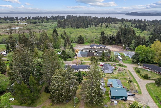 birds eye view of property featuring a water view and a wooded view