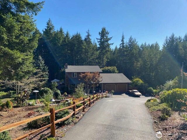 view of front facade with an attached garage, driveway, and a forest view