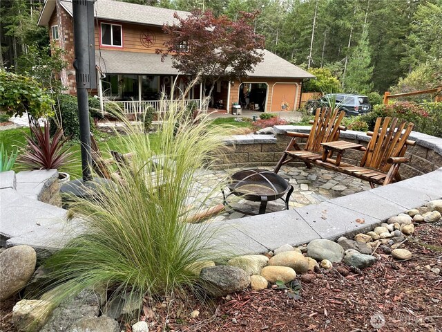 exterior space featuring a fire pit, a patio area, and a wooded view