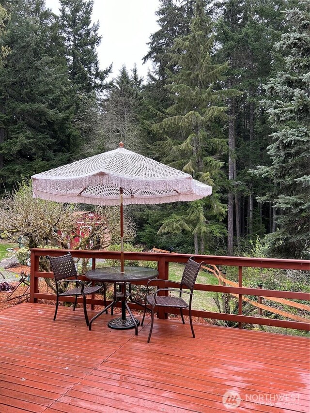 wooden terrace with outdoor dining space and a forest view