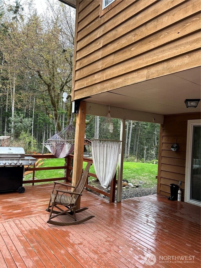 wooden terrace featuring area for grilling and a lawn