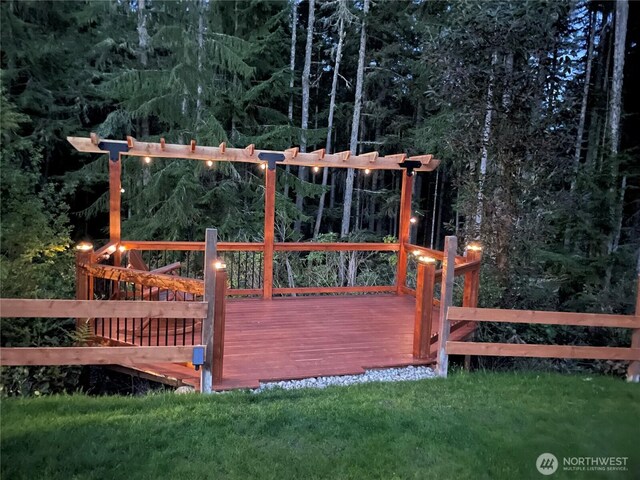 view of gate with a yard, a deck, and a forest view