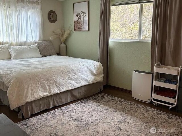 bedroom with baseboards, multiple windows, and wood finished floors