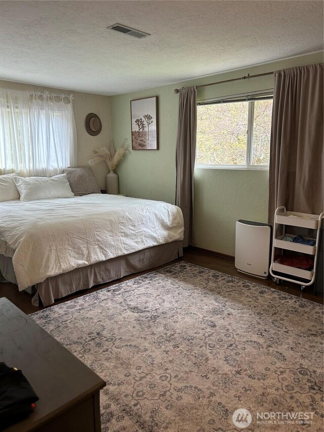 bedroom featuring visible vents, a textured ceiling, and wood finished floors