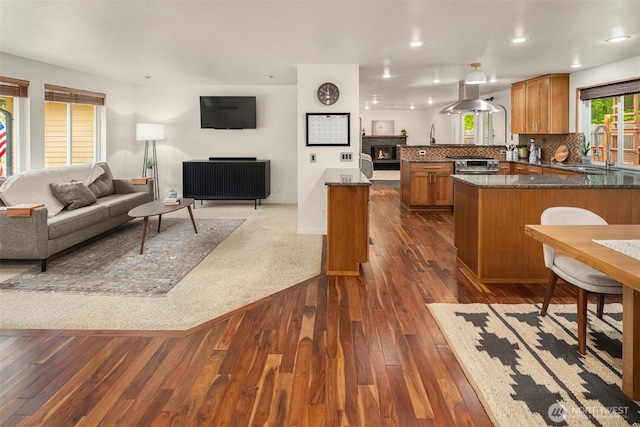 kitchen featuring a sink, brown cabinets, a peninsula, and open floor plan