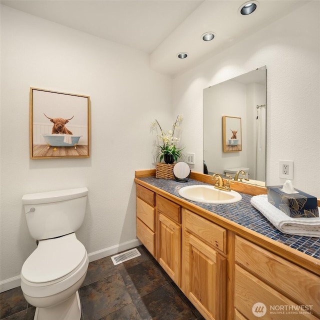 bathroom with stone finish flooring, visible vents, baseboards, vanity, and toilet