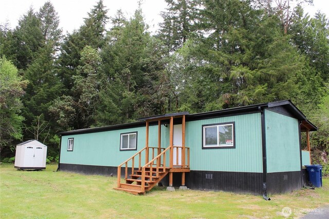 manufactured / mobile home featuring an outdoor structure, a shed, entry steps, and a front lawn