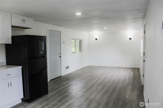 kitchen with visible vents, freestanding refrigerator, wood finished floors, baseboards, and white cabinets