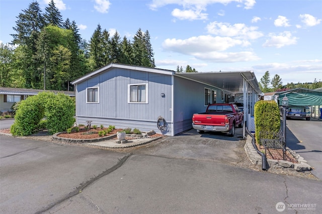 manufactured / mobile home with asphalt driveway and a carport
