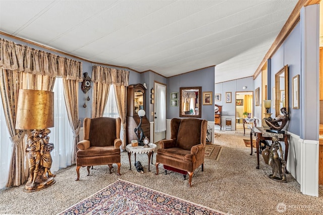 carpeted living area with crown molding and vaulted ceiling
