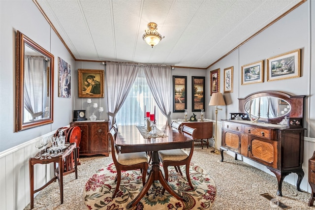 dining area featuring crown molding, a textured ceiling, light carpet, and wainscoting