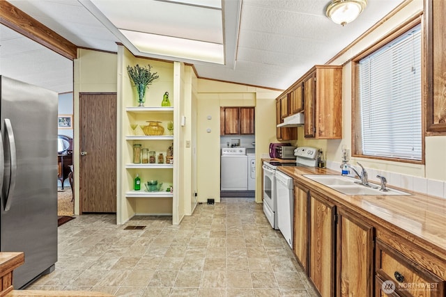 kitchen with freestanding refrigerator, a sink, washer and dryer, under cabinet range hood, and electric range