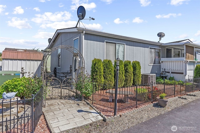 view of side of property featuring fence, central air condition unit, and a gate