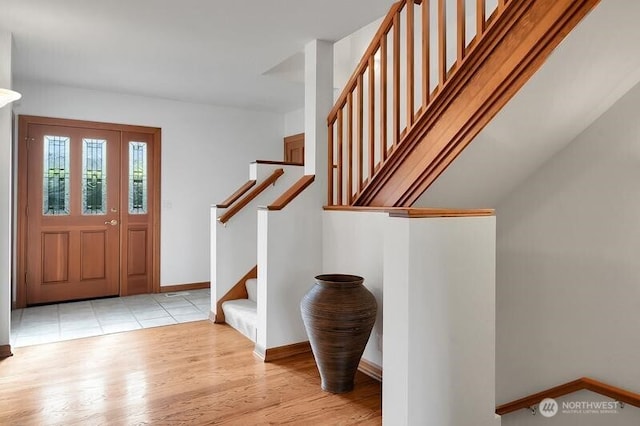 entrance foyer featuring baseboards, stairs, and light wood-type flooring