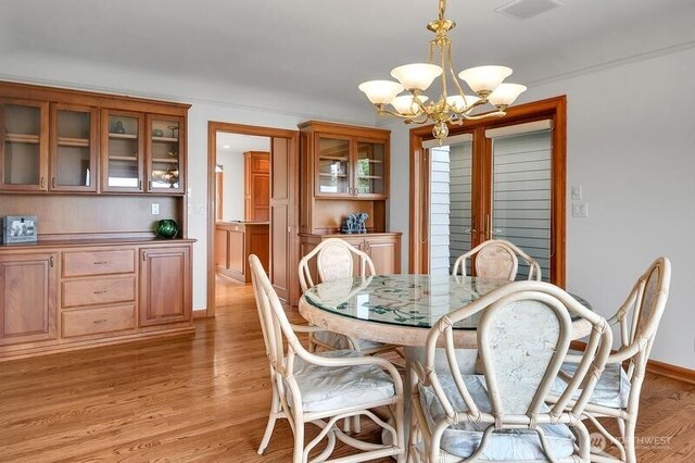 dining space featuring baseboards, an inviting chandelier, visible vents, and light wood-style floors
