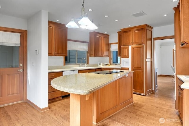 kitchen with a sink, light countertops, light wood-style floors, and black electric stovetop