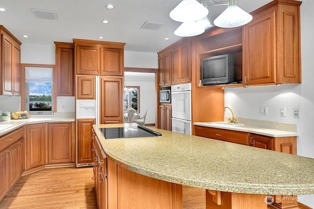 kitchen with black electric stovetop, recessed lighting, light wood-type flooring, built in microwave, and a sink