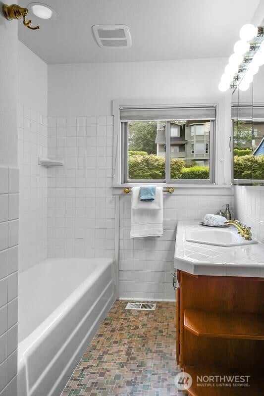 bathroom with tile walls, plenty of natural light, and visible vents