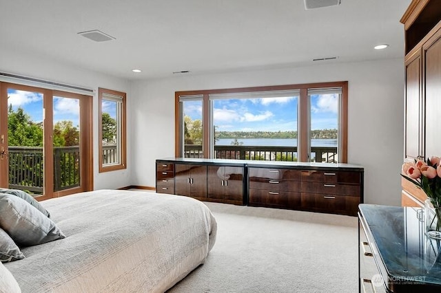 bedroom with light colored carpet, recessed lighting, and a water view