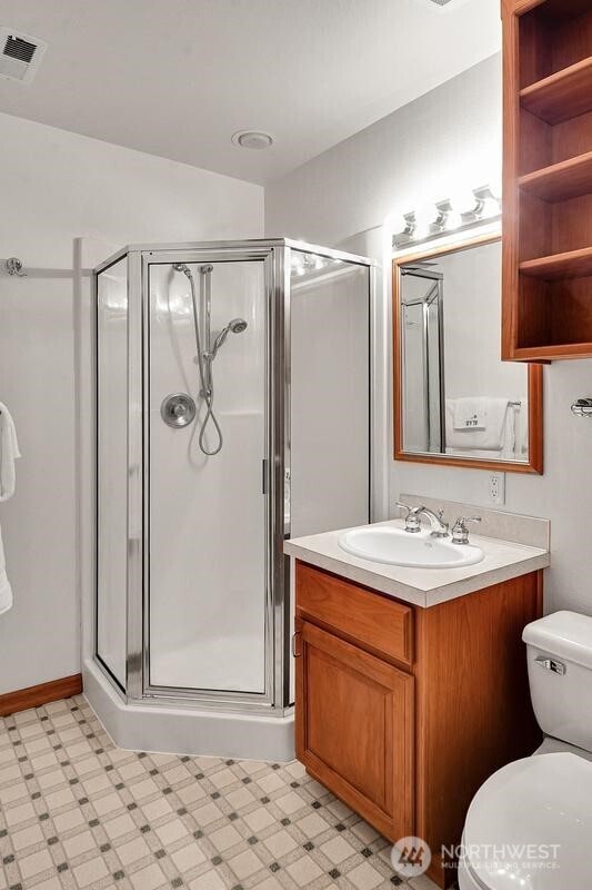full bathroom featuring visible vents, a stall shower, vanity, tile patterned floors, and toilet