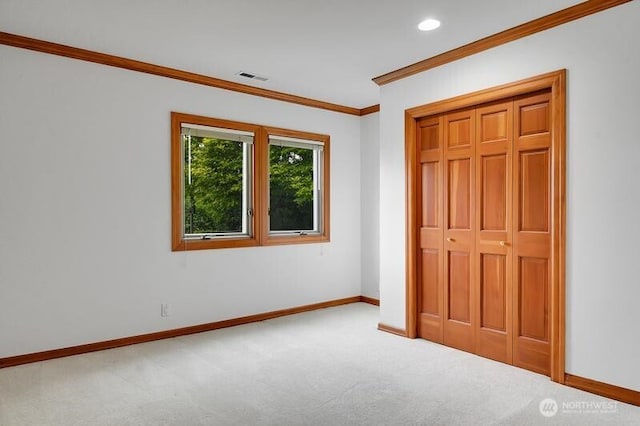 unfurnished bedroom with crown molding, carpet floors, baseboards, and a closet