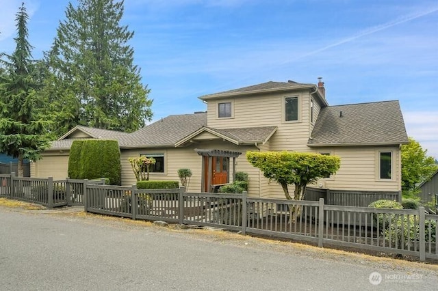 view of front of home featuring fence, a chimney, and a shingled roof