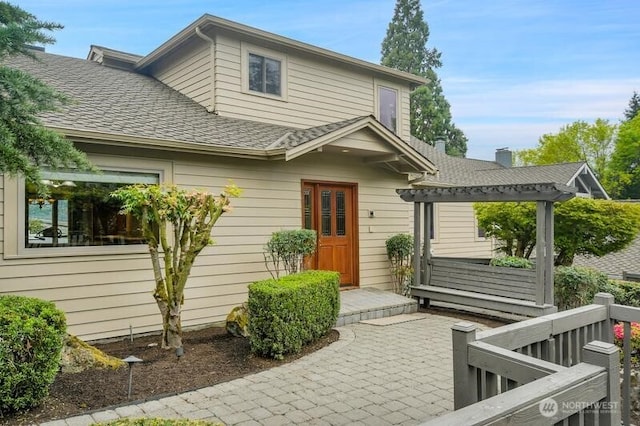 exterior space with a pergola and roof with shingles