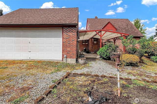 tudor-style house featuring roof with shingles and brick siding