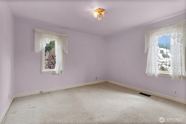 empty room with carpet floors, plenty of natural light, baseboards, and visible vents