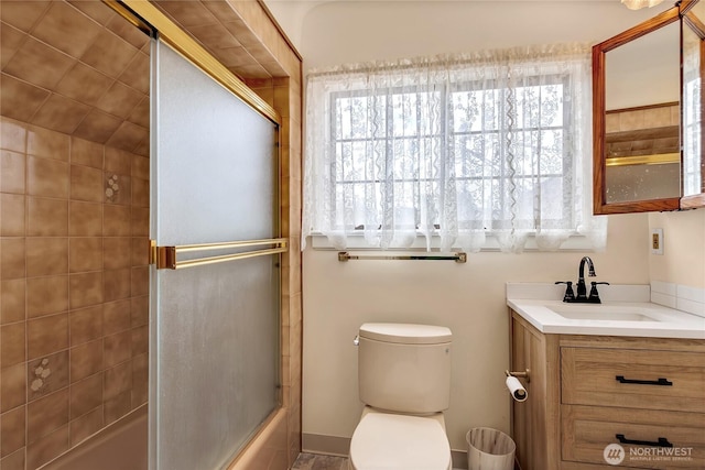 bathroom featuring vanity, bath / shower combo with glass door, and toilet